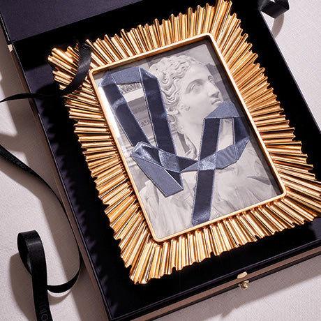 Decorative gold frame with a classical sculpture design on a light background