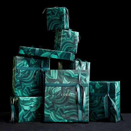 Stack of green patterned boxes with 'L'OBJET' branding on a black background